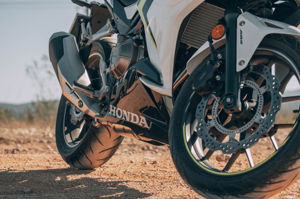 Detailed view of a Honda motorcycle's wheel and exhaust outdoors.